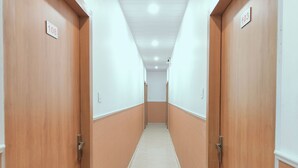 A hallway with wooden doors, white walls, and a tiled floor. - Hotel Golden Oak Near Golden Temple (Amritsar)