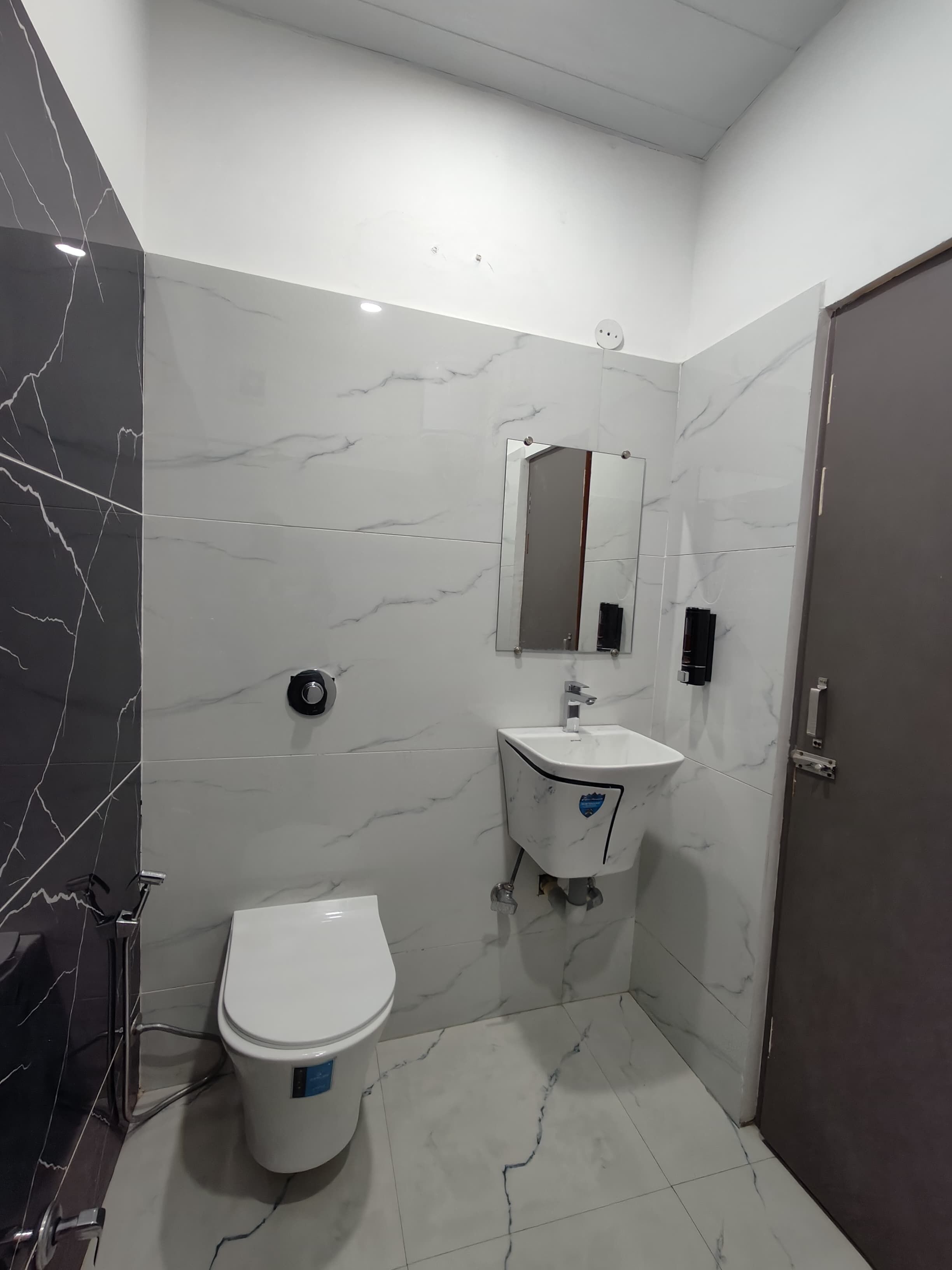A bathroom with a toilet, sink, and mirror.