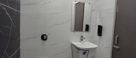 A bathroom with a toilet, sink, and mirror.