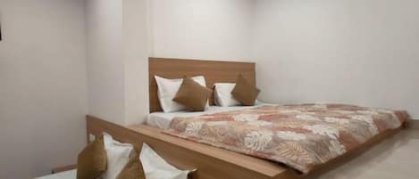A bedroom with a wooden bed frame, two single beds, and a large bed with a floral bedspread.