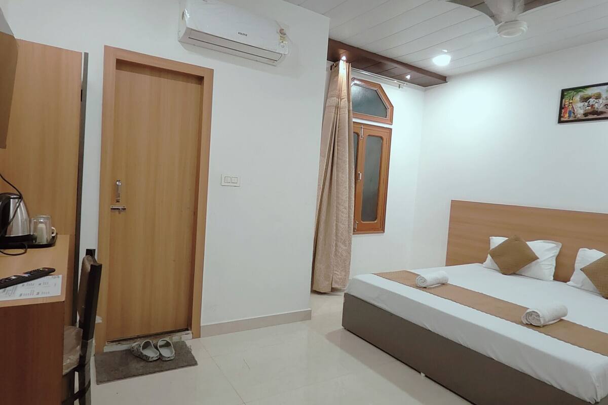 Hotelkamer met een bed, een kledingkast, een airconditioning en een plafondventilator, en een schilderij aan de muur.