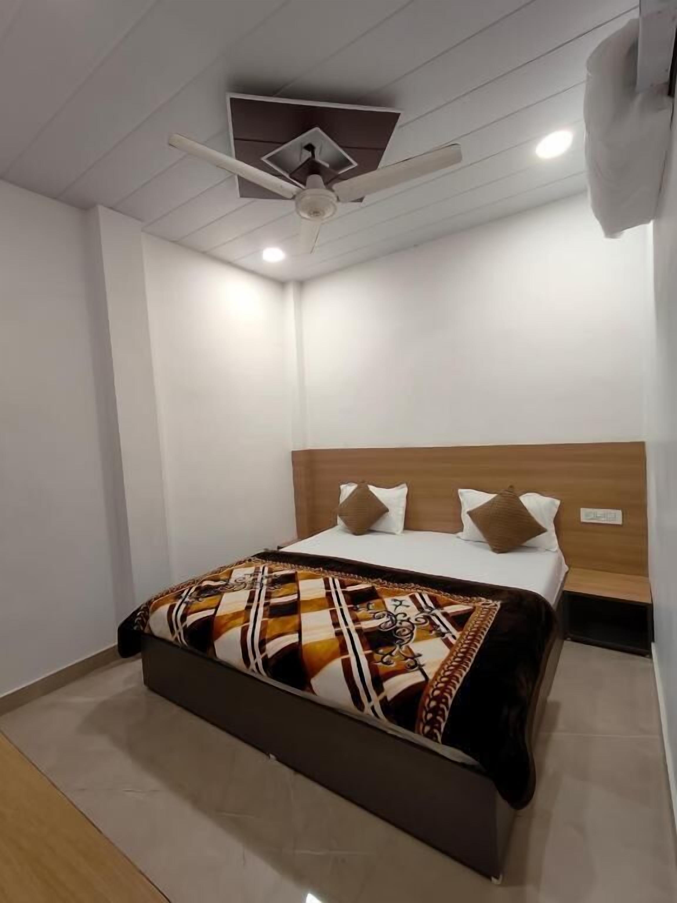 Una habitación de hotel moderna con una cama grande, un ventilador de techo y un cabecero de madera.