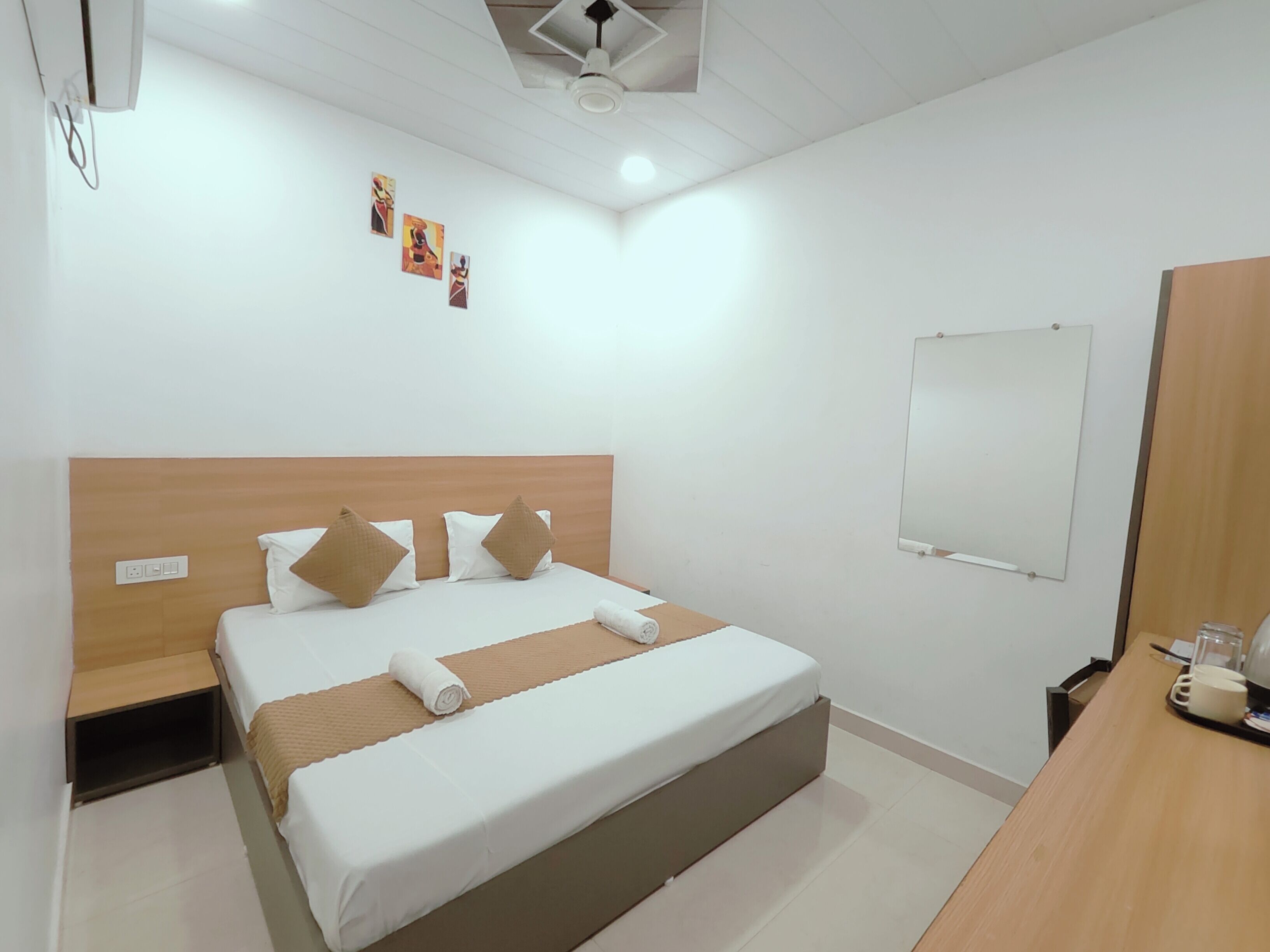 A hotel room with a bed, bedside tables, a desk, and a mirror.