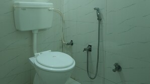 A small, clean bathroom with a toilet, a shower, and a wall-mounted sink. - Comfort Meets Elegance Orchha ,“Your Perfect Stay, Every Time (Orchha)