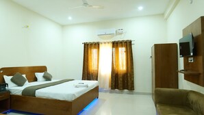 A hotel room with a bed, a TV mounted on the wall, a wardrobe, and a ceiling fan. - Comfort Meets Elegance Orchha ,“Your Perfect Stay, Every Time (Orchha)