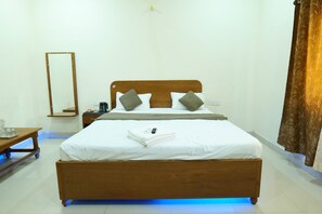 Ein Schlafzimmer mit einem hölzernen Bett, weißer Bettwäsche, zwei Kissen, einem Nachttisch mit Lampe, einem Spiegel und einem Vorhang.