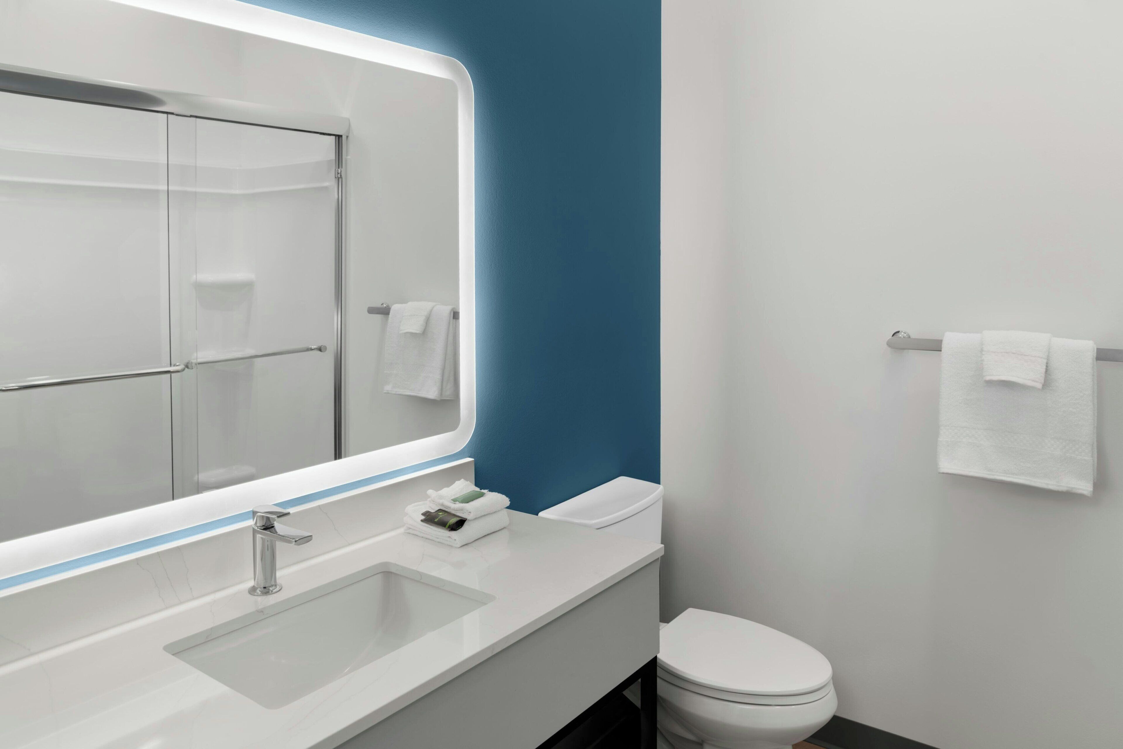 Un baño moderno con un espejo grande, un lavamanos y un inodoro.
