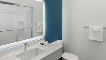 Un baño moderno con un espejo grande, un lavamanos y un inodoro.
