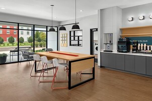 Un espacio de oficina moderno con una mesa de madera, sillas blancas y una estación de café.