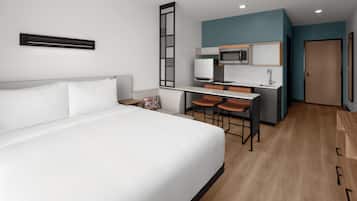 A hotel room with a bed, a desk with two chairs, a microwave, and a sink.