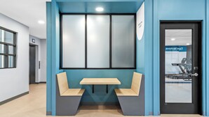 A modern waiting area with a bench, a table, and a door with a sign. - StudioRes by Marriott Memphis Cordova (Cordova)