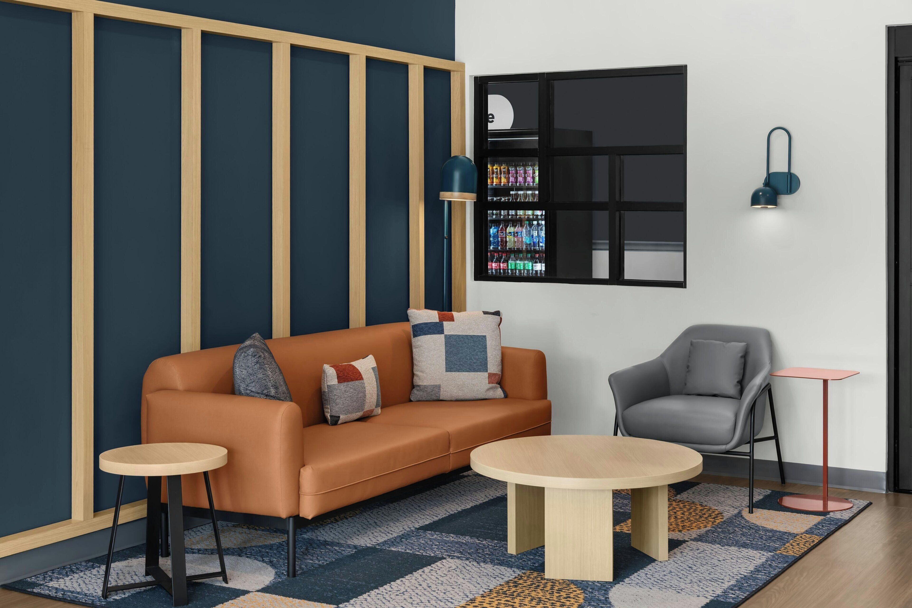 A modern living room with a sofa, two side tables, a grey armchair, and a small table.