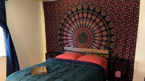 Un dormitorio con una cama, un tapiz, un cabecero de madera y una mesita de noche.