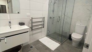 A modern bathroom with a glass shower enclosure, a white sink, and a toilet. - Central Albany, Popular modern 3 Beds +1 Carpark apartment (Auckland)