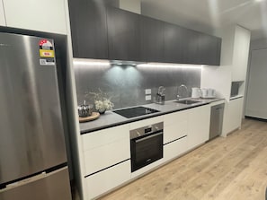 A modern kitchen with stainless steel appliances, a black countertop, and white cabinetry. - Central Albany, Popular modern 3 Beds +1 Carpark apartment (Auckland)