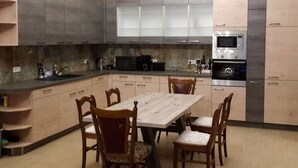Een keuken met een backsplash van bakstenen, houten kastjes, een ingebouwde magnetron en een eettafel met stoelen.