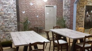 Een eethoek met een bakstenen muur, houten tafels en stoelen.
