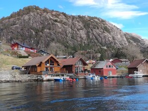 A waterfront property with cabins, a dock with boats, and a mountain backdrop. - The pearl of the Lysefjord - the boathouse at Prekestolen (Rogaland)