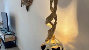 A modern interior with a unique wooden sculpture in a cylindrical planter, a minimalist desk setup, and a wall-mounted decorative piece. - T3 - 4/6 pers air-conditioned in Belgodère - Heated swimming pool, Lozari beach 1.5 km (Belgodère)