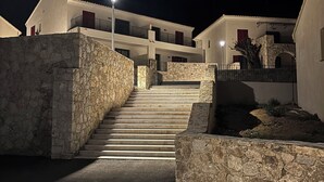 A nighttime view of a building with stone steps leading to a white facade with balconies. - T3 - 4/6 pers air-conditioned in Belgodère - Heated swimming pool, Lozari beach 1.5 km (Belgodère)