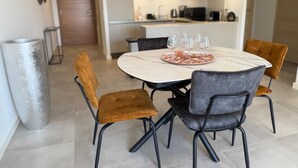 A modern kitchen with wooden cabinets, a marble countertop, and a dining area with a round table and four chairs. - T3 - 4/6 pers air-conditioned in Belgodère - Heated swimming pool, Lozari beach 1.5 km (Belgodère)