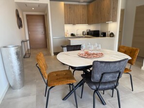 A modern kitchen with wooden cabinets, a marble countertop, and a dining area with a round table and four chairs. - T3 - 4/6 pers air-conditioned in Belgodère - Heated swimming pool, Lozari beach 1.5 km (Belgodère)