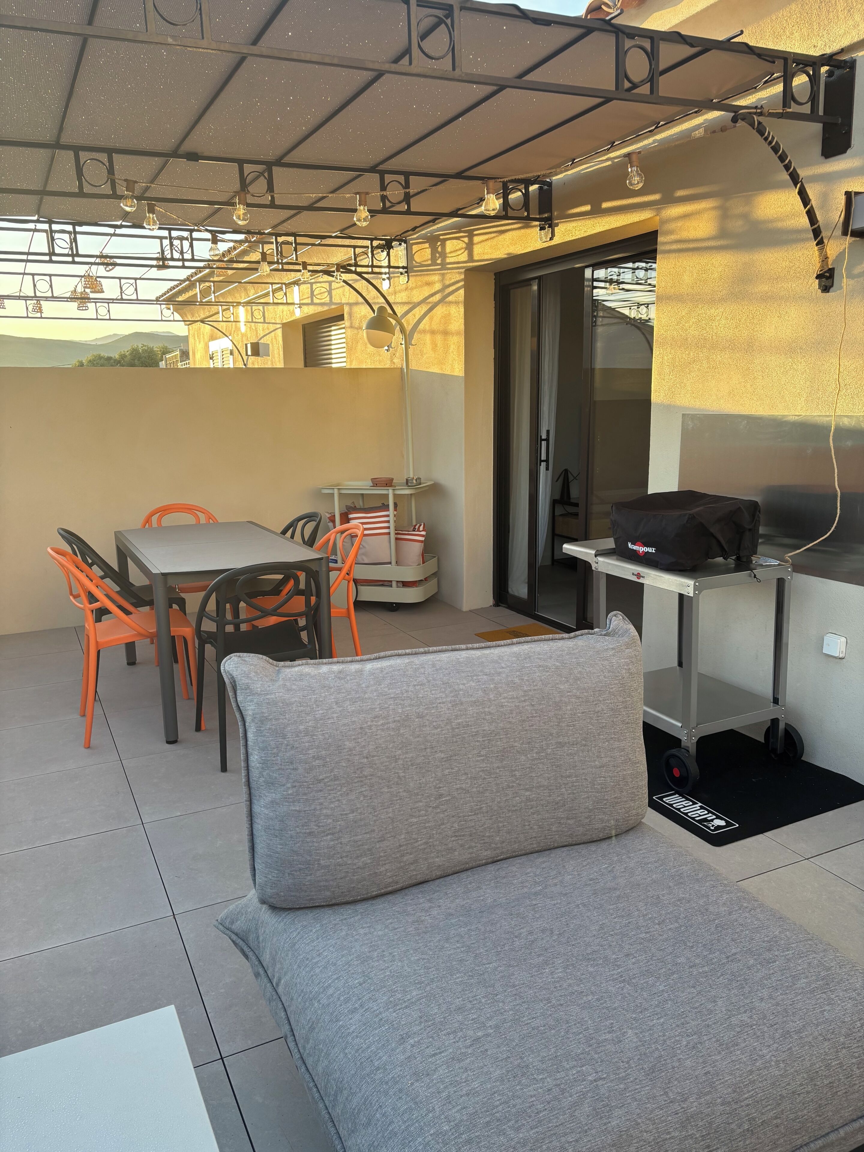 A covered outdoor seating area with a table, chairs, and a sofa.