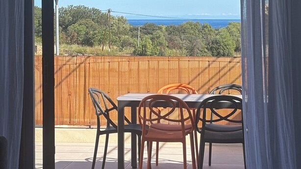 A balcony with a table and chairs, a view of the sea, and a bamboo fence. - T3 - 4/6 pers air-conditioned in Belgodère - Heated swimming pool, Lozari beach 1.5 km (Belgodère)