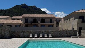 A rectangular swimming pool with clear blue water, surrounded by stone walls and a row of empty lounge chairs. - T3 - 4/6 pers air-conditioned in Belgodère - Heated swimming pool, Lozari beach 1.5 km (Belgodère)