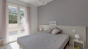 Een slaapkamer met een bed, nachtkastjes, een lamp en uitzicht door een schuifdeur.