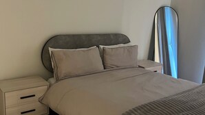 Ein Schlafzimmer mit einem Bett, einem Nachttisch, einem Spiegel und einer Wand.