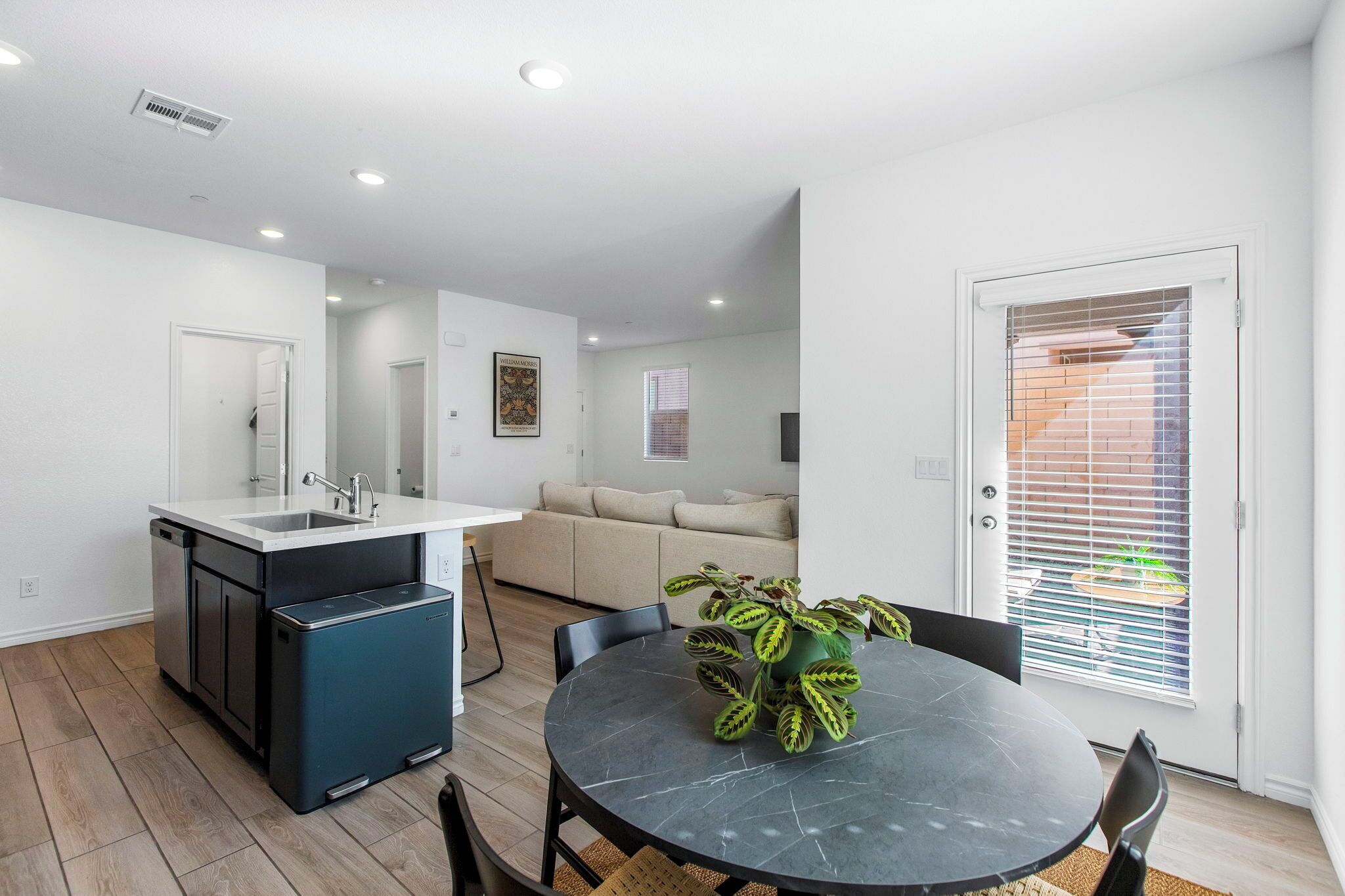 A modern kitchen with a dishwasher, a sink, and a dining area with a table and chairs.