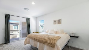 Une chambre à coucher avec un lit, une fenêtre, une porte et un balcon.