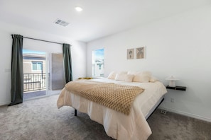 A bedroom with a bed, a window, a door, and a balcony. - Spacious Henderson Home w/ Large Office (Henderson)