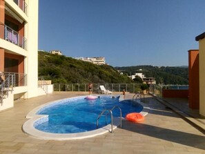 Ein Pool im Freien mit Blick auf eine Hügel- und Gebäudelandschaft im Hintergrund.