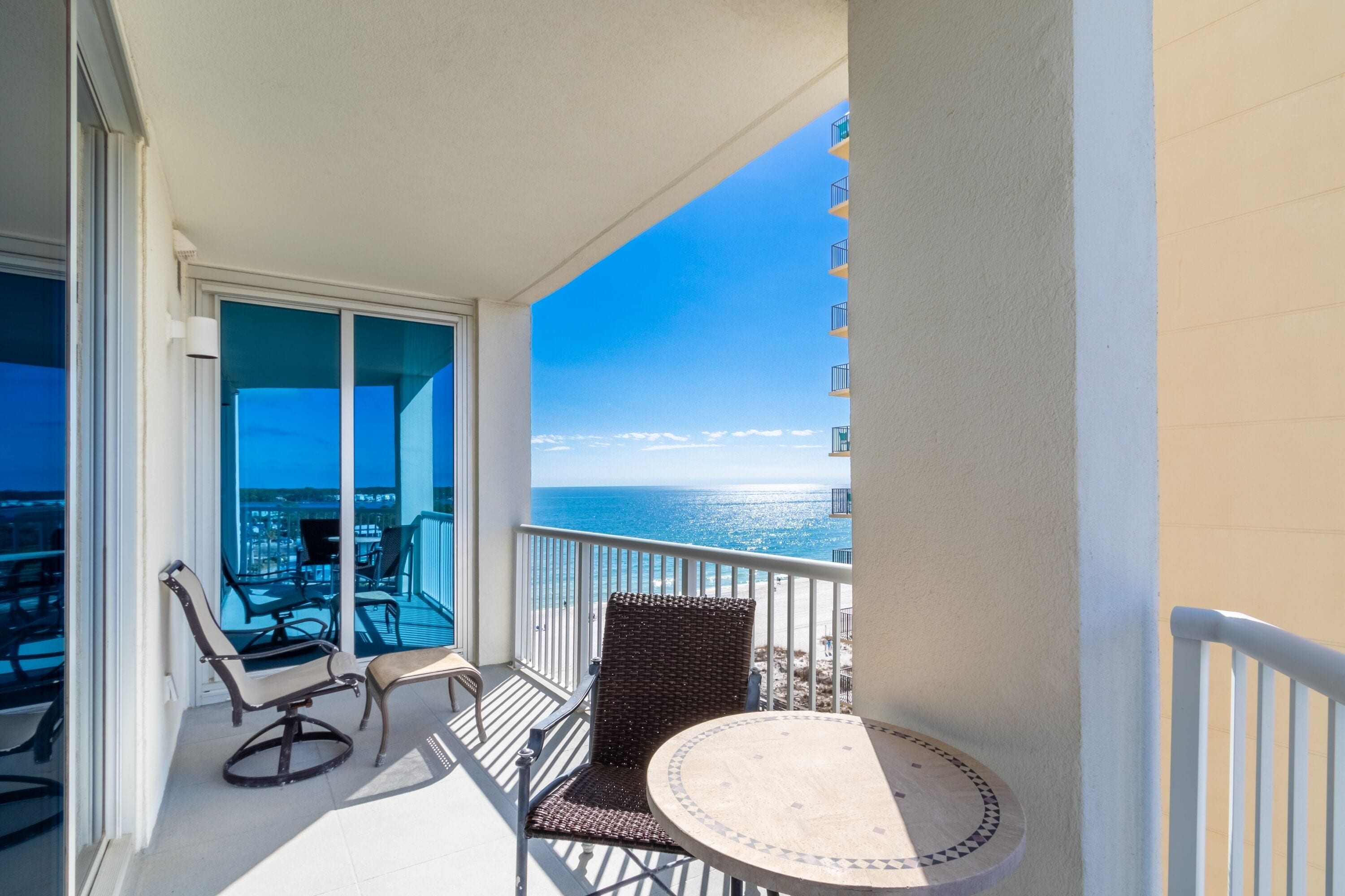 A balcony with a view of the ocean, a round table, and two chairs.