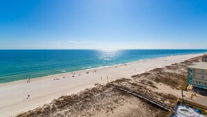 Ein Strand mit blauem Himmel, sandigem Ufer und einem Gebäude mit grüner Dachbegrünung.
