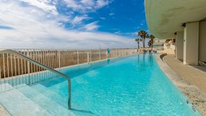 A swimming pool with clear blue water, a metal ladder, and a white fence. - Island Tower Condos (Gulf Shores)
