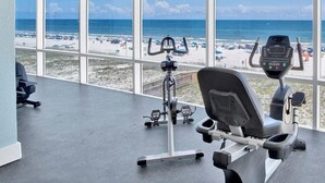 Ein Fitnessstudio mit Blick auf den Strand und den Ozean durch große Fenster.