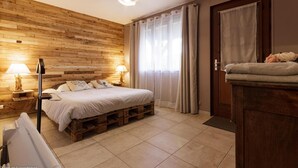 Ein Schlafzimmer mit Holzwand, einem Bett mit weißer Bettwäsche, zwei Nachttischlampen und einer Tür mit Handtuch und Blumen.