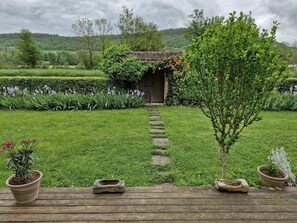 A rustic wooden deck with potted plants and a stone pathway leading to a wooden structure with a tiled roof. - Le petit Flotteur at the gateway to Morvan (Chevroches)