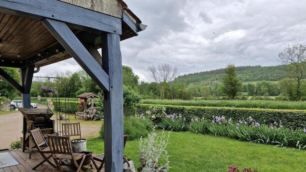 Eine Holzterrasse mit Gartenmöbeln, einem Grill und Topfpflanzen.