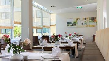 A restaurant with tables set for dining, large windows, and a modern interior design.
