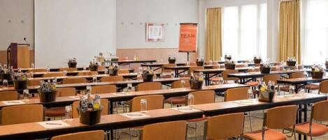 A conference room with multiple tables and chairs, a podium, and a presentation screen.