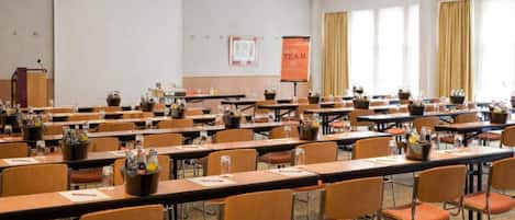 A conference room with multiple tables and chairs, a podium, and a presentation screen.