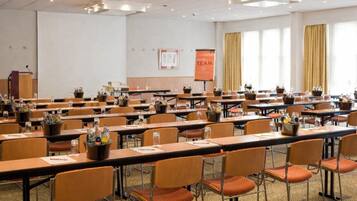 A conference room with multiple tables and chairs, a podium, and a presentation screen.