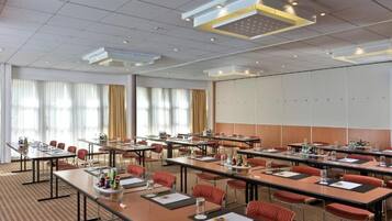 A conference room with multiple tables, chairs, and a large whiteboard.