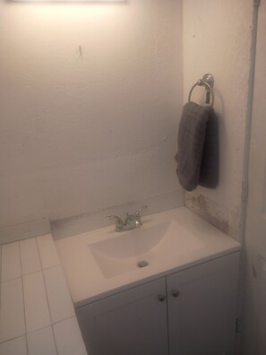 Ein Badezimmer mit einem weißen Waschbecken, einem Handtuchhalter mit zwei Handtüchern und einem Schrank darunter.