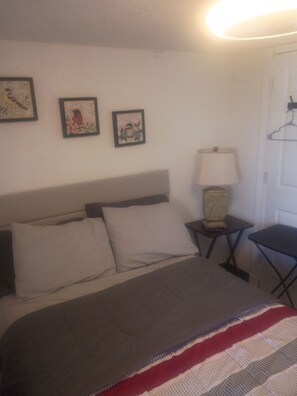 Ein Hotelzimmer mit Bett, Nachttisch, Lampe und Wandbildern.