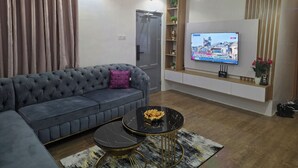 Ein modernes Wohnzimmer mit einem grauen Sofa, einem schwarzen Couchtisch und einem an der Wand befestigten Fernseher.